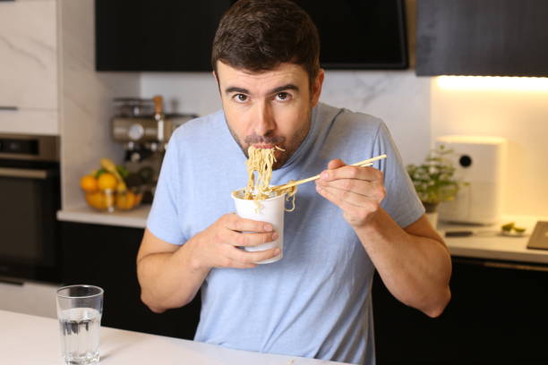istock Cute guy eating instant noodles 1449062068