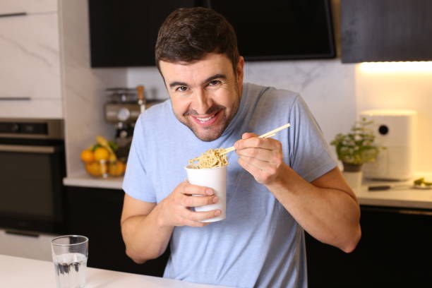 istock Cute guy eating instant noodles 1449062070