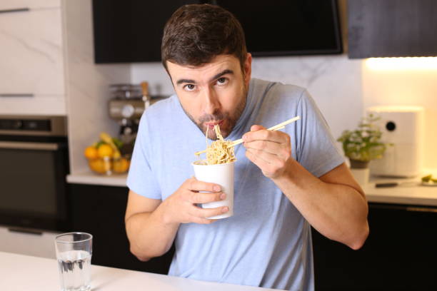 istock Cute guy eating instant noodles 1449062108