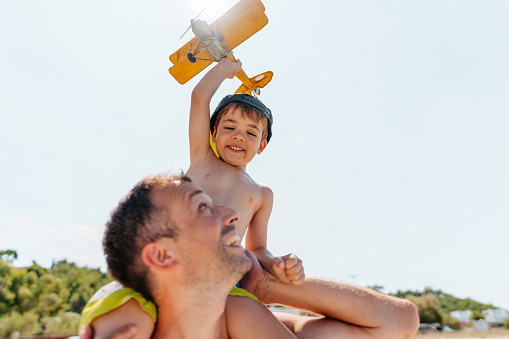 Photo of father and son playing with an airplane toy at the beach