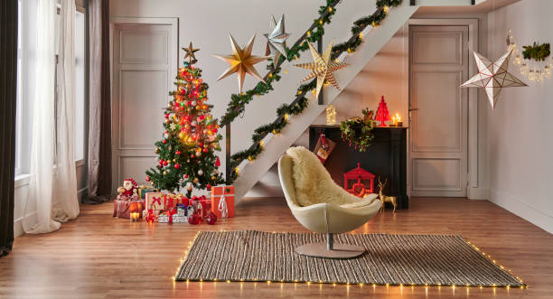 istock Modern sofa Christmas New Year concept with pine tree gift box and fireplace, decorative led lamp, stairs and door background, grey wall, wicker carpet design. 1449063223