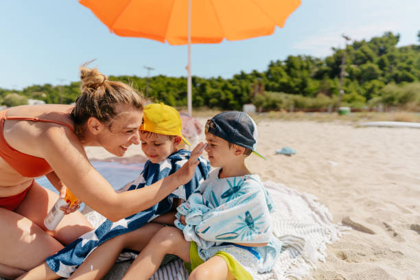 istock Mother applying sunscreen to her boys while at the beach 1449063795