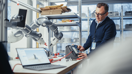 Creative Engineering Robotsa Male Senior Developer Works On Engineering Project Changes Robotic Hand ...