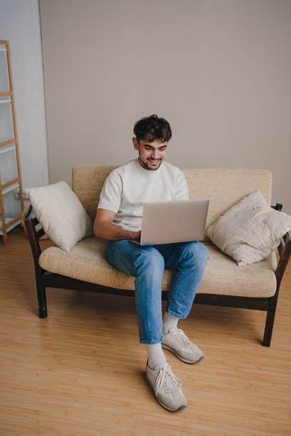 istock Young man working on a laptop as he relaxing on a comfortable sofa at home. Internet communication. Happy lifestyle. 1449063903