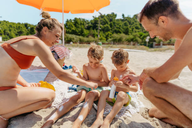 istock Happy family applying sunscreen while at the beach 1449063971