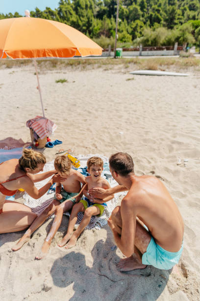 istock Happy family applying sunscreen while at the beach 1449064029