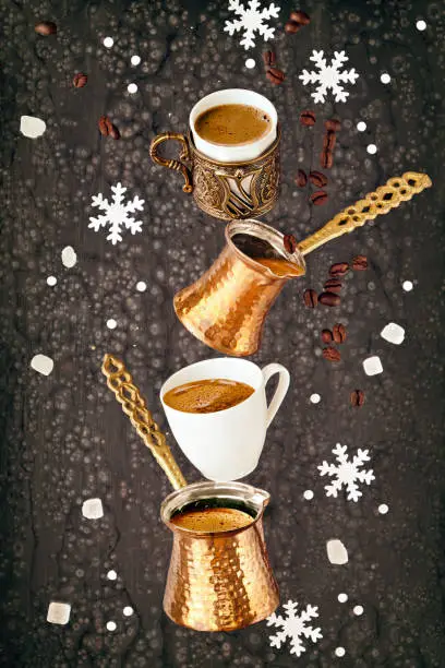 Balancing pyramid of jezves, turkish coffee pots and cups on dark background with coffee beans and sugar