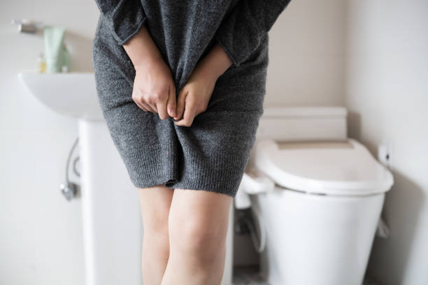 incontinence A woman wearing knitwear is complaining of pain from urinary incontinence in front of the toilet bladder stock pictures, royalty-free photos & images