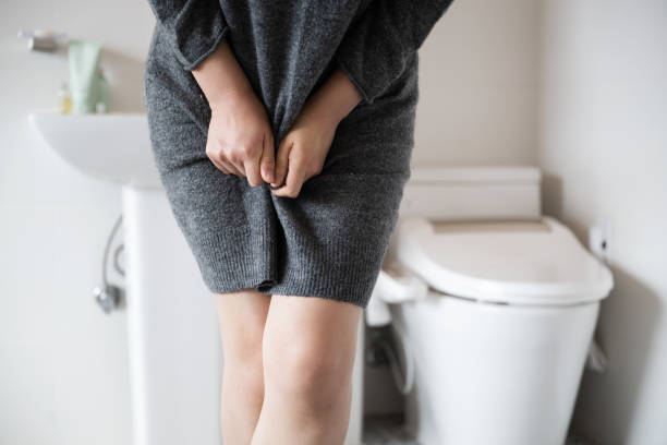 incontinence A woman wearing knitwear is complaining of pain from urinary incontinence in front of the toilet urinary tract infection stock pictures, royalty-free photos & images