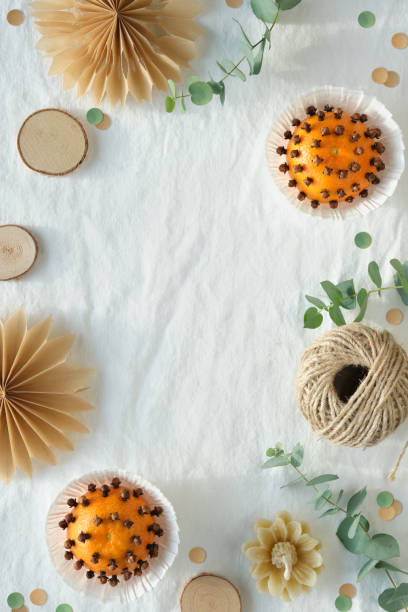 istock Fragrant pomander balls handmade from tangerines and cloves. Flat lay on off white textile tablecloth with aromatic wintertime green eucalyptus twigs. 1449074981