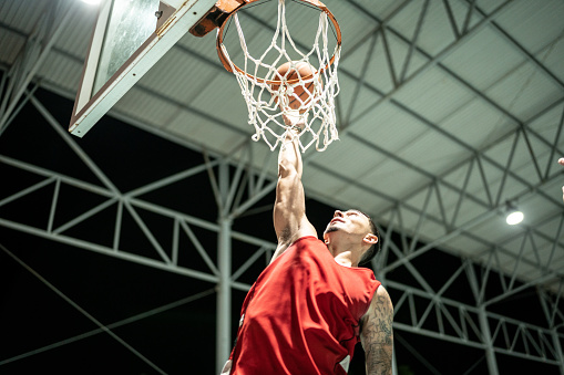 Basketball player makes slam dunk at a basketball court