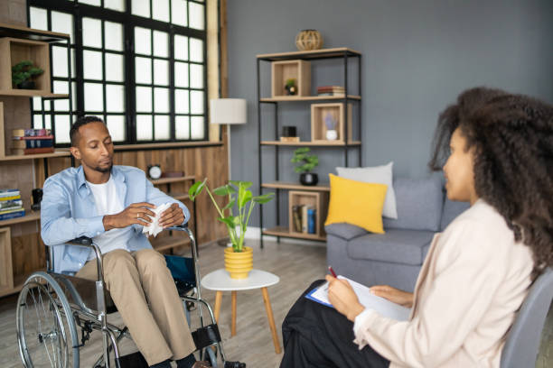 istock Man in wheelchair talks with therapist 1449081442