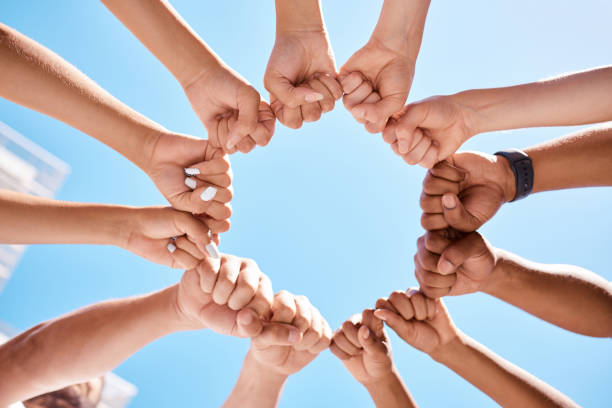 istock Fist hands, circle and community support diversity people, protest group and freedom fight on blue sky background. Below solidarity, teamwork and motivation for justice goal, trust and society power 1449081468