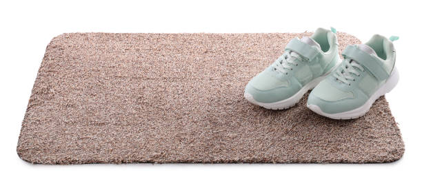istock Stylish door mat with shoes on white background 1449082515