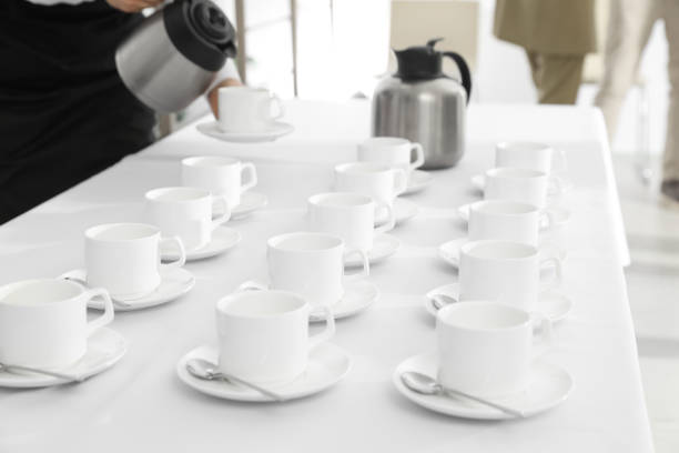 istock Waitress pouring hot drink during coffee break, focus on table with cups 1449083454