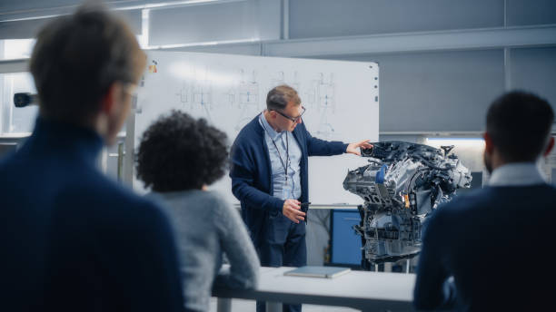 istock Male Teacher Talks About Engineering to Students And Points at Whiteboard. Smart Future Scientists Listen Attentively and Look at Engine. Industry 4 Sustainable Energy Research and Education Concept. 1449083606