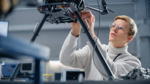 istock Young Male Engineer Programming on Laptop. Working on a New Drone Software in the Research Center Laboratory. People Designing Futuristic Unmanned Aerial Vehicle Concept. 1449084175