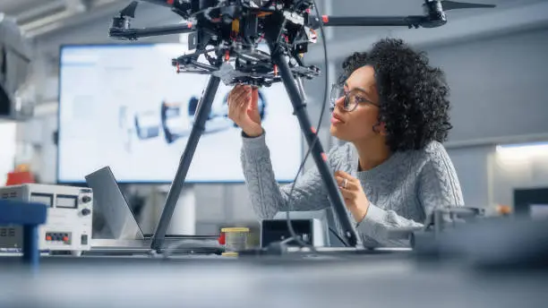 Photo of Concentrated Black Female Engineer Writing Code. Developing Software for Modern Drone Control in the Research Center Laboratory. Technological Breakthrough in Flight Industries Concept.