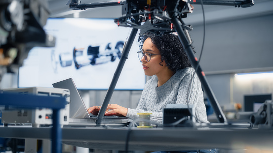 Concentrated Black Female Engineer Writing Code. Developing Software for Drone Control in the Research Center Laboratory. Technological Breakthrough in Flight Industries Concept.