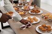 People near table with different delicious snacks during coffee break, closeup