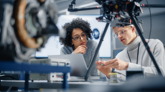 Diverse Engineers Discussing New Powerful Microchip to Put it Inside the Modern Drone. Technological Startup and Innovative Technologies in Unmanned Aerial Vehicle Concept.