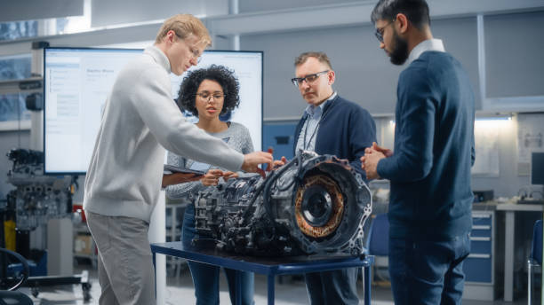istock Intelligent Black Woman Talks to Diverse Colleagues While Working Together on Functions Modification of Electric Engine. Engineering and Sustainable Energy Innovative Technologies Concept. 1449084734