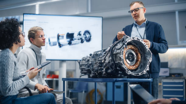 istock Diverse Specialists Gathering around Engine and Discussing it with Male Chief Engineer During Seminar. Research, Development, Visualisation, Digitalisation of Green Electric Energy Concept. 1449085104