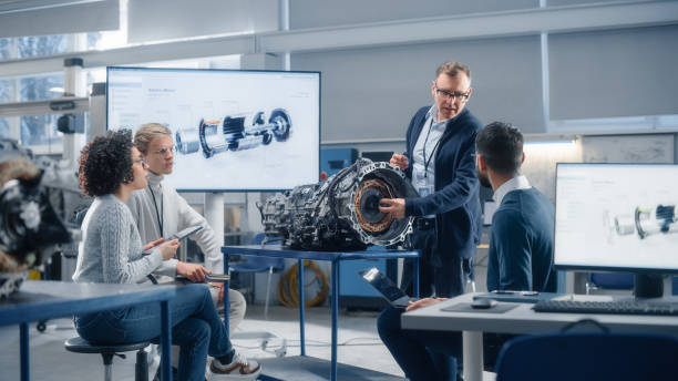 team of diverse engineers using laptop and tablet to analyse electric vehicle engine in the research laboratory. modern industry 4 sustainable energy and emission reduction technology concept. - energiebesparing fotos stockfoto's en -beelden