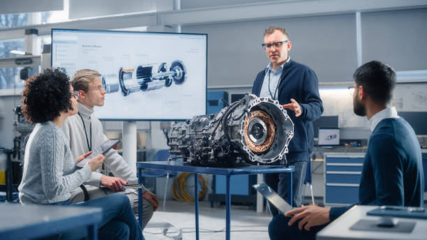 istock Team of Diverse Engineers Using Laptop and Tablet to Analyse Electric Vehicle Engine In the Research Laboratory. Modern Industry 4 Sustainable Energy and Emission Reduction Technology. 1449085708