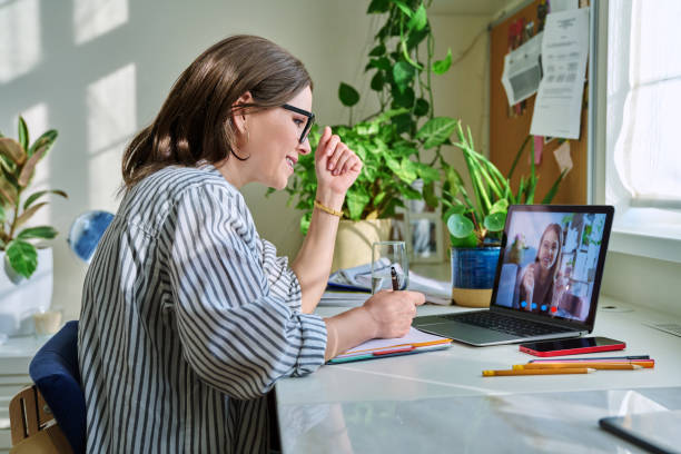 Middle aged woman having video conference on laptop with young woman stock photo