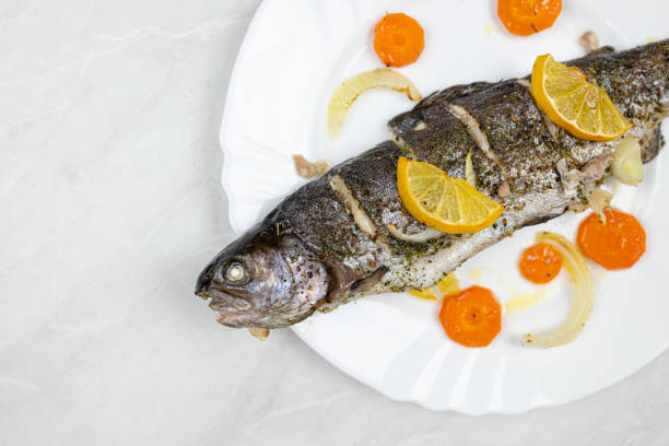 Baked trout served on the plate with vegetables stock photo