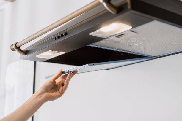 mujer instalando nuevo filtro de campana en la cocina - range hood fotografías e imágenes de stock