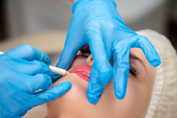 istock Caucasian Beautician Accomplishing Permanent Make-up on Female Lips Using Cotton Sticks. 1449092943