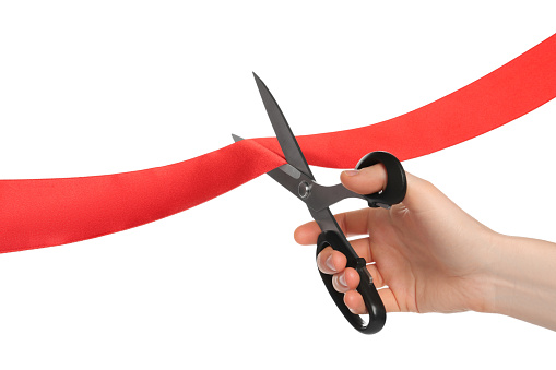 Man cutting red ribbon on white background, closeup