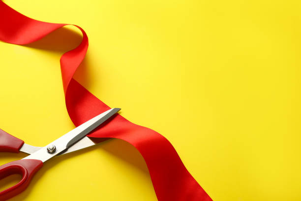 istock Red ribbon and scissors on yellow background, top view. Space for text 1449093126