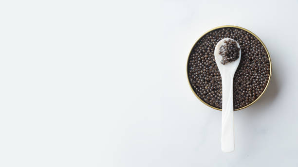 Black caviar in a mother-of-pearl spoon Black caviar in a mother-of-pearl spoon Horizontal banner on a white background with a copy space caviar stock pictures, royalty-free photos & images