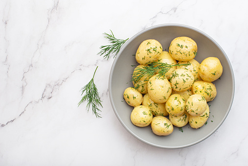 Boiled potatoes with dill on a gray background