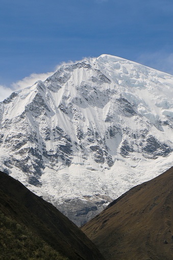 A vertical shot of the snow-covered peak of the mountain during the daytime