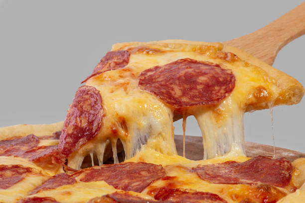 istock Slice of pizza with pepperoni and stretching cheese on a gray background 1449098700
