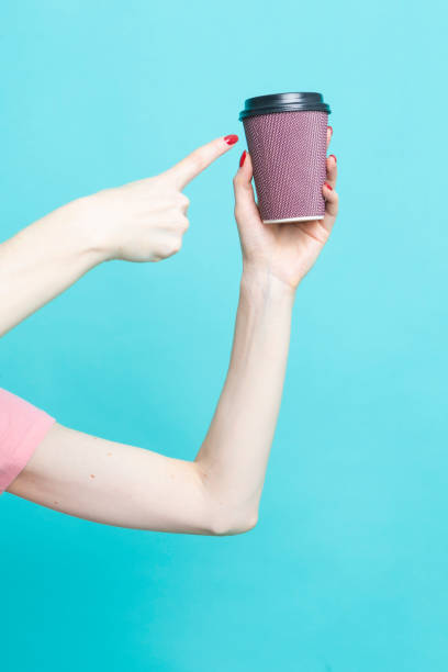 Hand of Young Caucasian Woman While Drinking Holding Cup of Coffee Over Blue Aqua Background And Pointing to Cup with Hand and Finger