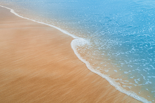 Close up detail of powerful teal blue wave breaking in open ocean on a bright sunny afternoon