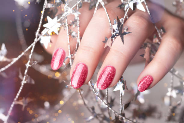 istock Hand with magenta glitter nails with tinsel 1449104931