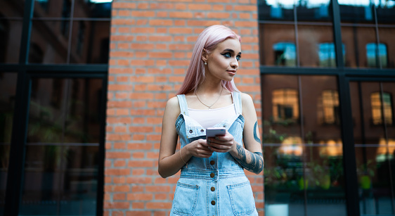 Image of young woman with colorful hair on university campus and holding sustainable coffee cup