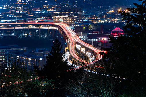 Shot from a high altitude vantage point, a busy city with traffic lights, large buildings, and overpasses. This image illustrates connection and travel. Shot in Portland Oregon.