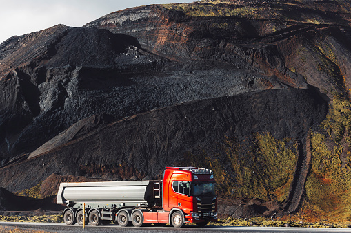 A red truck driving from the red stone quarry in Iceland. Volcanic red stone quarry, exploring Iceland, autumn time.