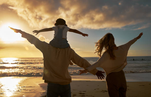 Family, summer and beach fun of a mother, dad and baby enjoying the ocean at sunset. Mama, feather and kid with happiness in nature by the sea water happy about vacation and quality time outdoor diversión familiar, de verano y de playa de una madre, un padre y un bebé disfrutando del océano al atardecer. mamá, padre e hijo con felicidad en la naturaleza junto al agua del mar felices por las vacaciones y el tiempo de calidad al aire libre