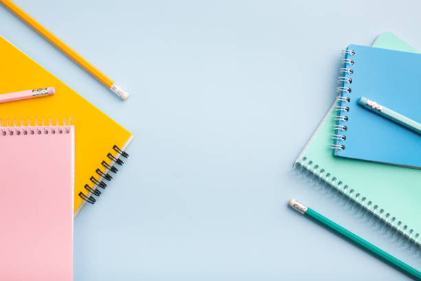 istock colored notebooks, colored pencils on a light table. Place for your text. 1449123098