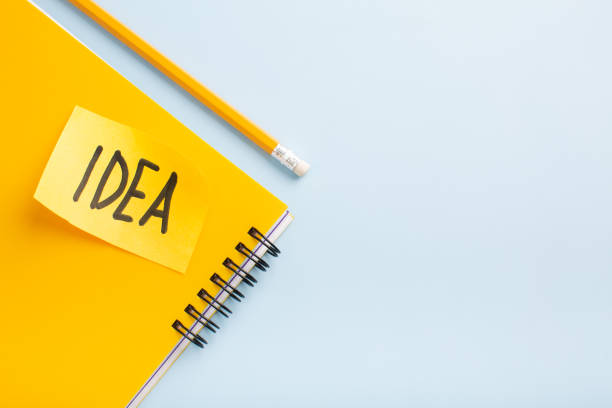 istock Yellow notepad lettering idea with a pencil on a blue background, place for your text 1449123252