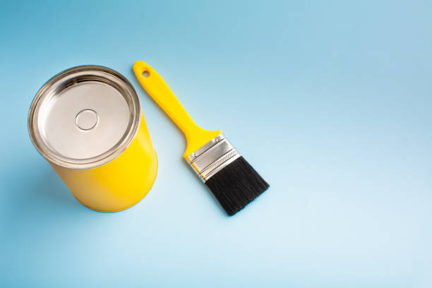 istock Yellow paint in a jar with a brush on a blue background 1449123976