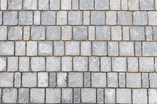 top view of a stone pavement made of gray rectangular bricks. smooth stones on the pavement, the texture of the stone surface